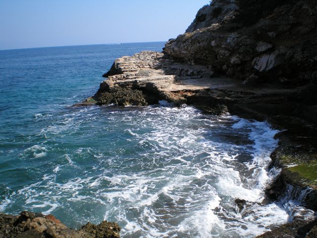 In una stupenda caletta, il sentiero si interrompe per farsi sommergere dal mare che siinfrange spumeggiante contro gli scogli rocciosi...